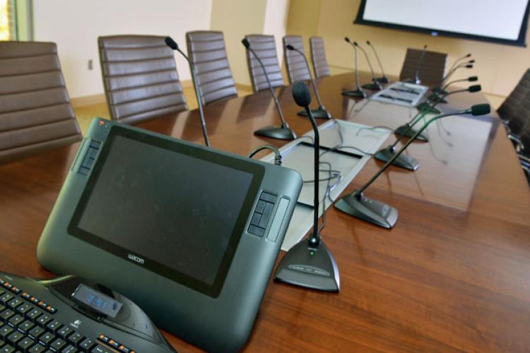 View of conference table featuring A/V monitor, screen, and microphones